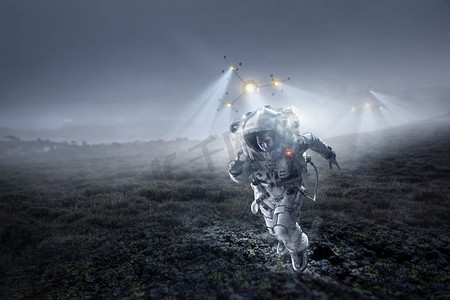 星球表面摄影照片_穿着宇航服的宇航员在行星表面运行。混合媒体。太空人跑得很快。混合媒体