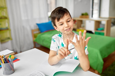 教育，童年和学校的概念—快乐的学生男孩计数使用手指在家里。男孩做作业和计数使用手指