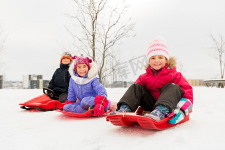 童年、雪橇和季节概念-一群快乐的小孩子在冬天滑雪橇。快乐的小孩子们在冬天滑雪橇