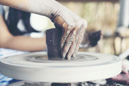 女人的双手合拢，精湛的陶瓷工作室用陶工的轮子上的粘土’’