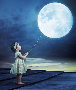 一个可爱的婴儿抱着一个月球气球的概念图像