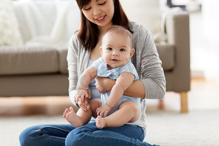 家庭和母亲的概念—快乐微笑的年轻亚洲母亲与小婴儿在家里。快乐的年轻母亲与小婴儿在家里