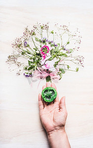 女性手掌持有绿色手工肥皂在白色背景与植物和花，顶视图天然化妆品概念
