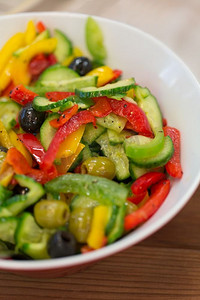 素食餐摄影照片_健康饮食，素食和烹饪概念—蔬菜沙拉特写镜头与橄榄碗。特写蔬菜沙拉在碗里