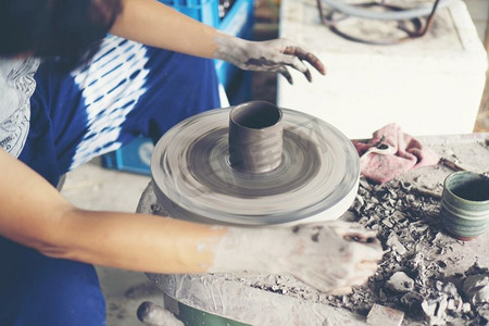 陶瓷工艺摄影照片_女人的双手合拢，精湛的陶瓷工作室用陶工的轮子上的粘土’’