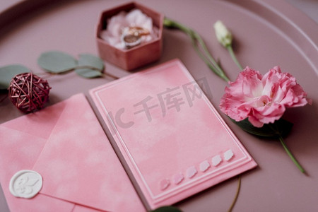 粉红色的婚礼邀请在灰色信封在一个桌子上与绿色小枝