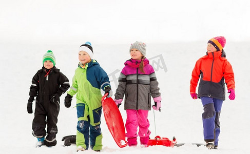 童年，雪橇和季节概念—一群快乐的小孩子在冬天雪橇。快乐的小孩子与雪橇在冬天