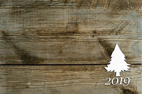 在2019年圣诞卡或新年背景的冷杉树形状的剪纸在木桌子上。桌上的冷杉形剪纸
