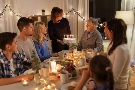 晚宴和庆祝概念—在家中用蛋糕庆祝祖父生日的快乐家庭。快乐的家庭有生日聚会在家里
