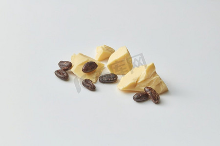 堆组成块有机生纯可可脂与棕色苦豆在灰色背景。可可豆和黄油块
