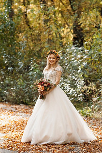 金发女郎在一件婚纱在秋天的森林