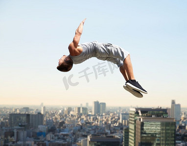 极限运动，跑酷和人的概念—年轻人跳高在东京城市背景。男子进行跑酷跳跃超过东京市