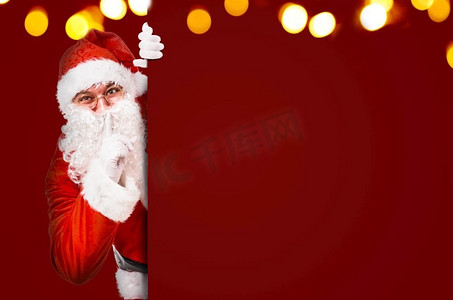 圣诞老人用手指放在嘴唇上，要求安静，上面有五颜六色的广告牌和文案空间。圣诞老人要求保持沉默