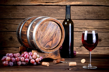 桌上放着一杯红葡萄酒和一抹葡萄。背景是木制的。。桌上放着一杯红葡萄酒和一抹葡萄。