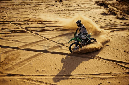 摩托车越野骑在沙漠沙丘的沙子。专业自行车飞行员极速赛车。摩托车越野骑在沙子在沙漠沙丘