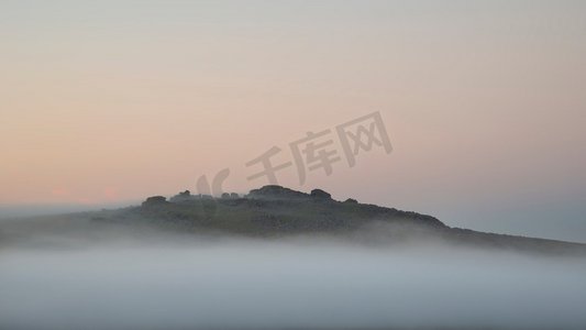 达特摄影照片_在达特穆尔的托尔斯上空，令人惊叹的雾蒙蒙的日出景观透过薄雾露出了山峰