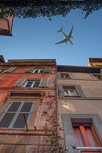 飞机飞过摄影照片_飞机飞过罗马古老的街道。