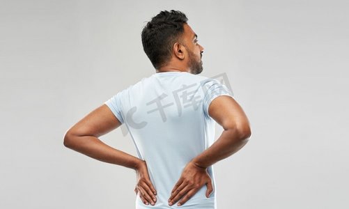 健康问题和人的概念—不幸的印度男子遭受背部或缰绳疼痛在灰色背景。印度男子背痛