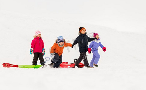 童年，雪橇和季节概念—一群快乐的小孩子在冬天雪橇。快乐的小孩子与雪橇在冬天