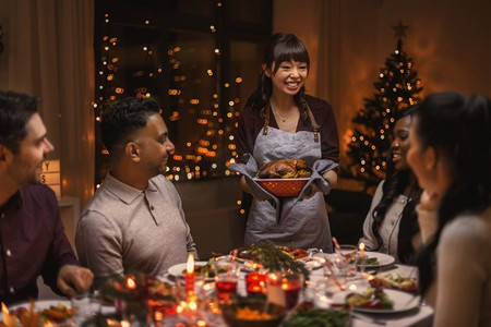 赢战鸡年摄影照片_节日和庆祝概念—多民族的快乐朋友在家里吃圣诞晚餐。快乐的朋友在家里吃圣诞晚餐
