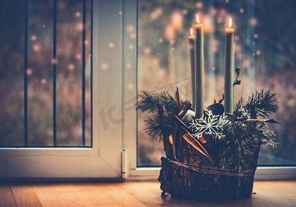 和平鸽花环摄影照片_圣诞节舒适的家与蜡烛在窗口。用燃烧的蜡烛献上降临节花环。冬季装饰室内与温暖的散景照明。