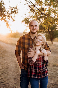 秋天木板背景摄影照片_日落时分，一个拿着木板的快乐的男人和一个穿着格子衬衫散步的金发女孩