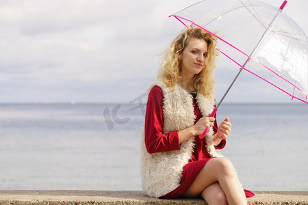 愉快优雅的成年妇女拿着透明伞反对天空。天气预报概念快乐的女人撑伞