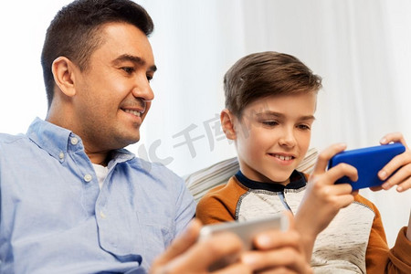 儿童智能摄影照片_休闲、科技、家庭和人的概念-家里有智能手机，幸福的父子。家中有智能手机的幸福父子