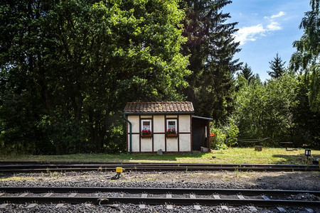 shack摄影照片_小房子靠近铁路与红色的花朵在夏天的窗户下