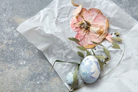 干花和鸡蛋在皱巴巴的纸和混凝土的背景上。纸上的鸡蛋