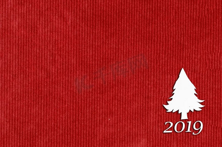 在红色桌子上圣诞卡或新年背景的冷杉树形状剪纸。桌上的冷杉形剪纸