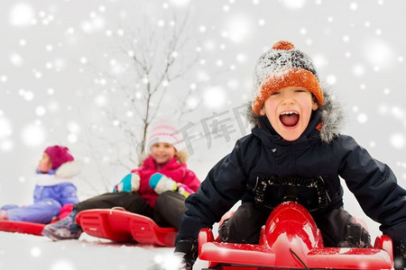 童年、雪橇和季节概念-一群快乐的小孩子在冬天滑雪橇。快乐的孩子们在冬天滑雪橇