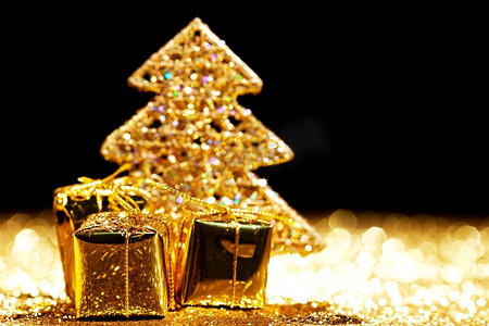 美丽的金色装饰圣诞树和礼物在金色闪光背景