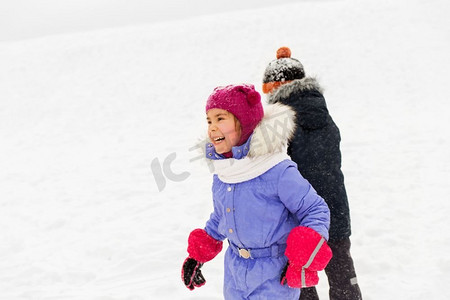 童年，休闲和季节的概念—快乐的小孩子在冬天的衣服玩户外。快乐的小孩子在冬天户外玩耍