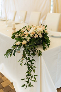 餐厅宴会厅的新婚夫妇主席团用蜡烛和绿植装饰，紫藤从天花板上垂下来