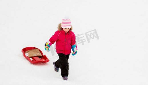 爬雪山摄影照片_童年，雪橇和季节概念—快乐的小女孩雪橇爬雪山在冬天。小女孩与雪橇在雪山在冬天