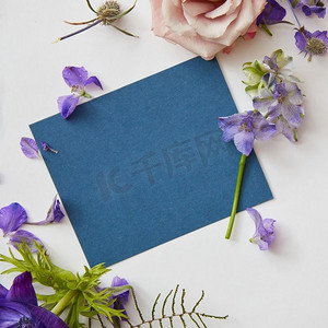 钜惠来袭邀请函摄影照片_框架春花用一张蓝色的纸下面的文字，平放。春天的花朵框架