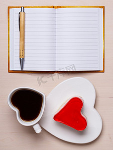 咖啡杯果冻蛋糕，心形和纸质空白笔记本，桌面上有钢笔，俯视文本空间