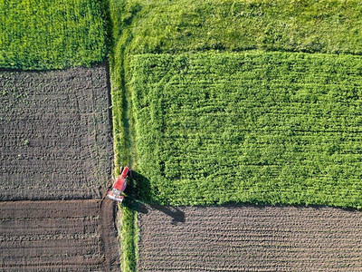 田野春天摄影照片_鸟瞰田野，耕地.拖拉机在地里工作。无人机的照片。农业鸟瞰农田在春天