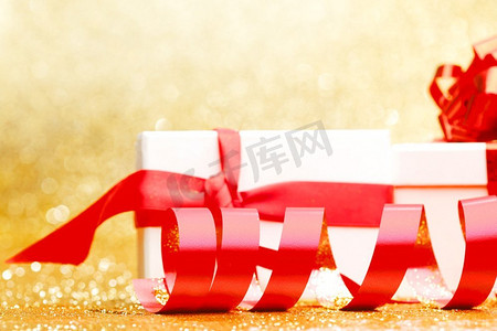 闪光框摄影照片_白色礼品盒与红丝带在金色闪光背景