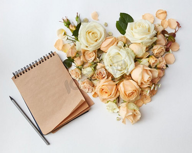 玫瑰花和记事本书的心脏在白色背景，平奠定。玫瑰花蕾如心