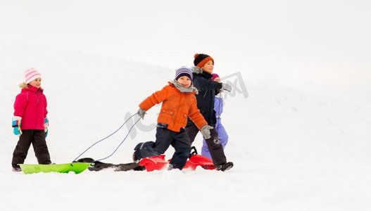 童年，雪橇和季节概念—一群快乐的小孩子在冬天雪橇。快乐的小孩子与雪橇在冬天