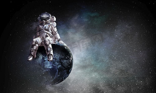 宇宙太空人摄影照片_太空人坐在地球上。这张照片的元素由NASA提供。混合媒体。宇宙中的太空人。混合媒体