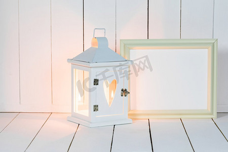 蜡烛灯笼用心脏和画框装饰在白色木背景。灯笼和相框
