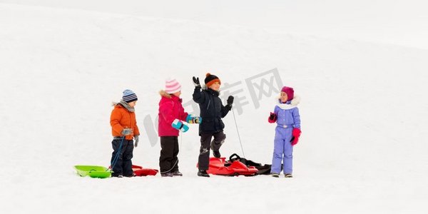 童年，雪橇和季节概念—一群快乐的小孩子在冬天雪橇。快乐的小孩子与雪橇在冬天