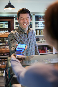 男性客户使用移动电话在熟食店做无接触支付购物 