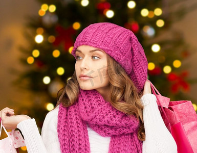 人，节日和销售概念--圣诞树上的购物袋女人的背景。拿着购物袋的女人挂着圣诞彩灯