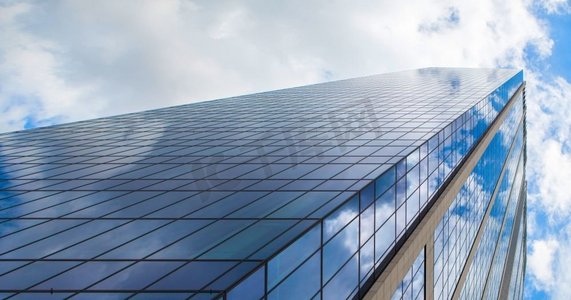 建筑企业摄影照片_现代玻璃办公楼反对蓝色多云的天空。现代建筑企业商务建筑