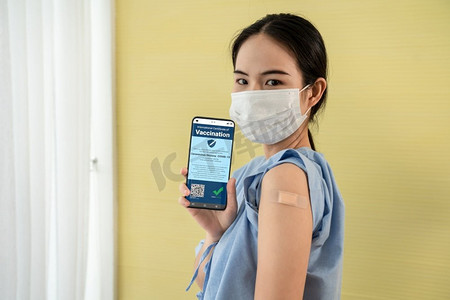一名年轻的亚洲女子在手机上出示疫苗护照，通过数字证件验证旅行许可。疫苗护照V2