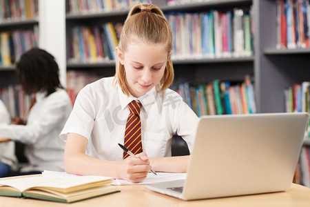女高中生穿着制服在笔记本电脑工作在图书馆